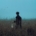 A man in a field at dawn holding a lantern.