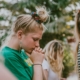 A young woman holding her hands to her chin with her head bowed and eyes closed.