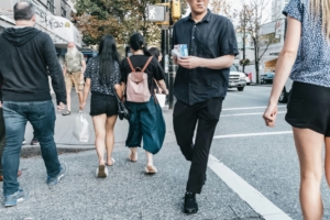 A busy street crosswalk in a city, full of people crossing the street.