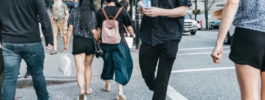 A busy street crosswalk in a city, full of people crossing the street.