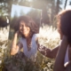 A woman in a field, looking at her reflection in a mirror.