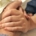 A close up of two white people holding hands. One person is wearing a hospital bracelet.