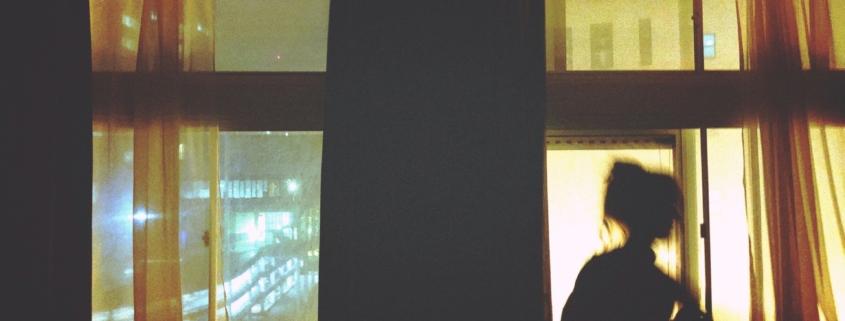A silhouette of a woman sitting in front of a window.
