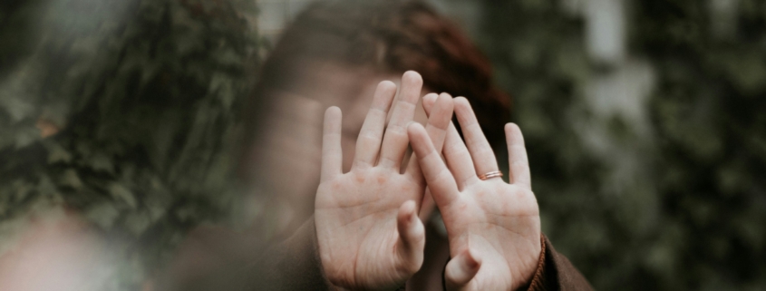 A white person holding their hands in front of their face like they don't want to be photographed.