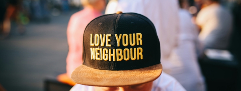 A man wearing a hat that says "Love your neighbour"