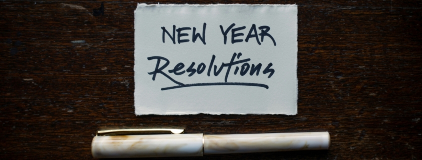A white piece of paper with "New Year Resolutions" written on it in black pen, on a dark background.