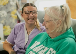 Two white women, one younger and one older, laughing together indoors.