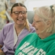 Two white women, one younger and one older, laughing together indoors.