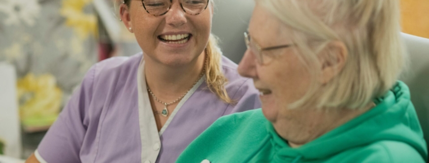 Two white women, one younger and one older, laughing together indoors.
