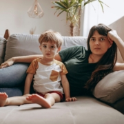 A white woman and child laying on a couch next to each other.