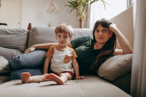 A white woman and child laying on a couch next to each other.