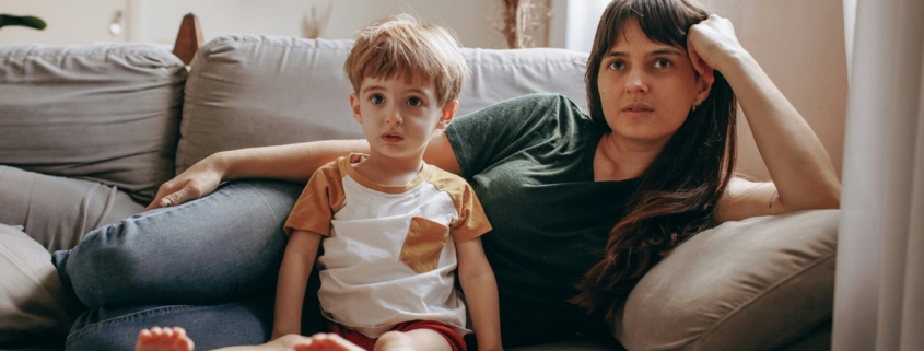 A white woman and child laying on a couch next to each other.