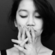 A black and white photo of an Asian woman looking sad and holding her hands up to her mouth like she's thinking.