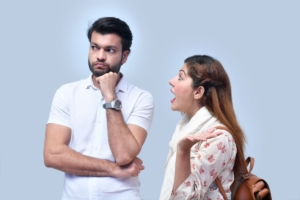 A man and a woman in front of a light blue background looking frustrated.