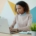 A Black woman at desk looking at a computer in front of a painted wall, looking stressed.