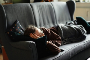 Woman in sweats laying on a gray couch